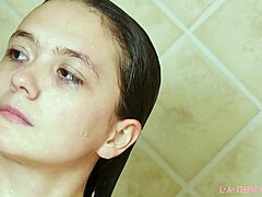 La modella bruna attraente si fa il bagno in una doccia calda