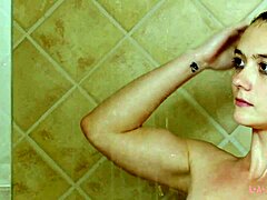 Attraktiv brunettemodell bader i en varm dusj