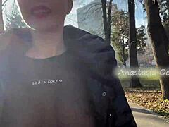 A stunning woman exposes her large breasts while strolling in a park