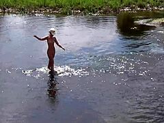 En mogen rysk kvinna tar ett naket bad utomhus